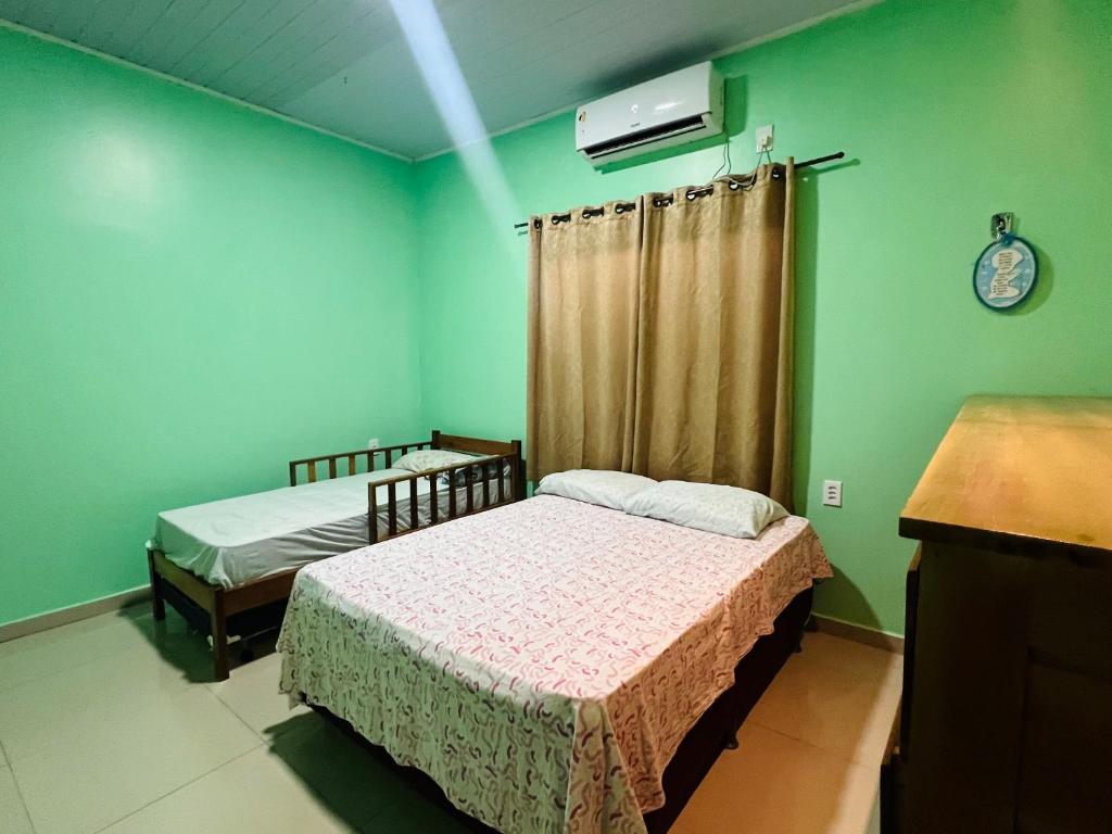 two beds in a room with green walls at Suíte completa em Parintins in Parintins