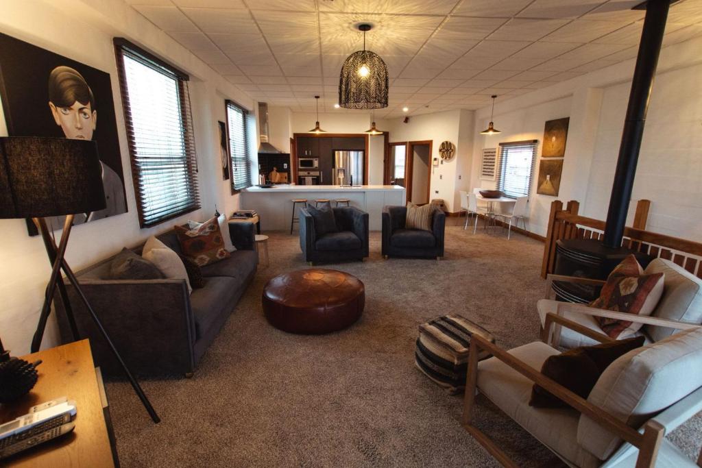 a living room with couches and chairs and a table at Stay Central The Penthouse in New Plymouth