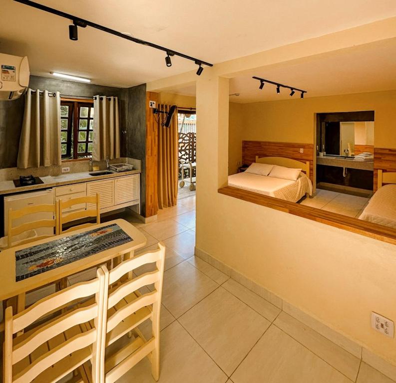 a bedroom with a bed and a table and a kitchen at Villa'l Mare Hotel in Maresias