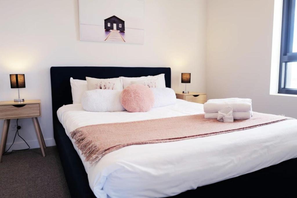 a bedroom with a large white bed with pink pillows at Lovely Home in midtown Box Hill with two bedrooms in Box Hill