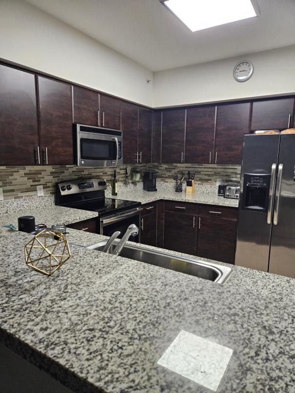 Coral gables apartment في ميامي: مطبخ مع أسطح من الجرانيت وأجهزة حديد قابلة للصدأ