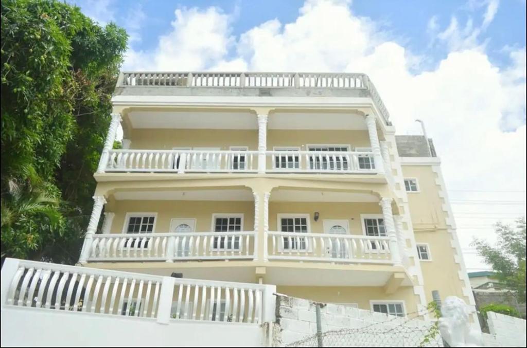 a large yellow building with a white balcony at Spacious Home away from Home! 1 Bedroom in Kingstown