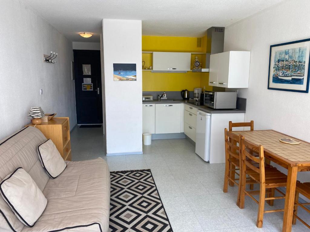 un salon et une cuisine avec un canapé et une table dans l'établissement Studio cosy avec piscine, parking et balcon à Gruissan - FR-1-784-13, à Gruissan