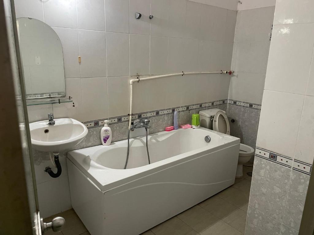 a bathroom with a tub and a sink and a toilet at Khách sạn Hoàng Bảo Hùng in Ho Chi Minh City