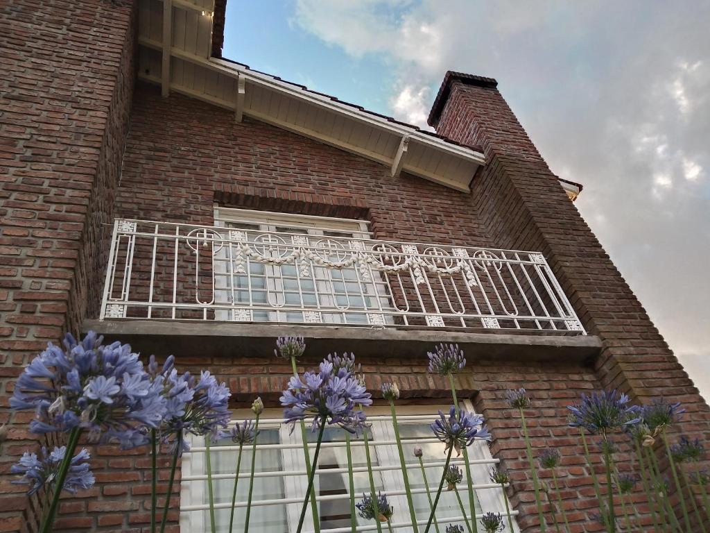 un balcón en un edificio de ladrillo con flores púrpuras en Casa de Campo El Duraznillo en Tandil
