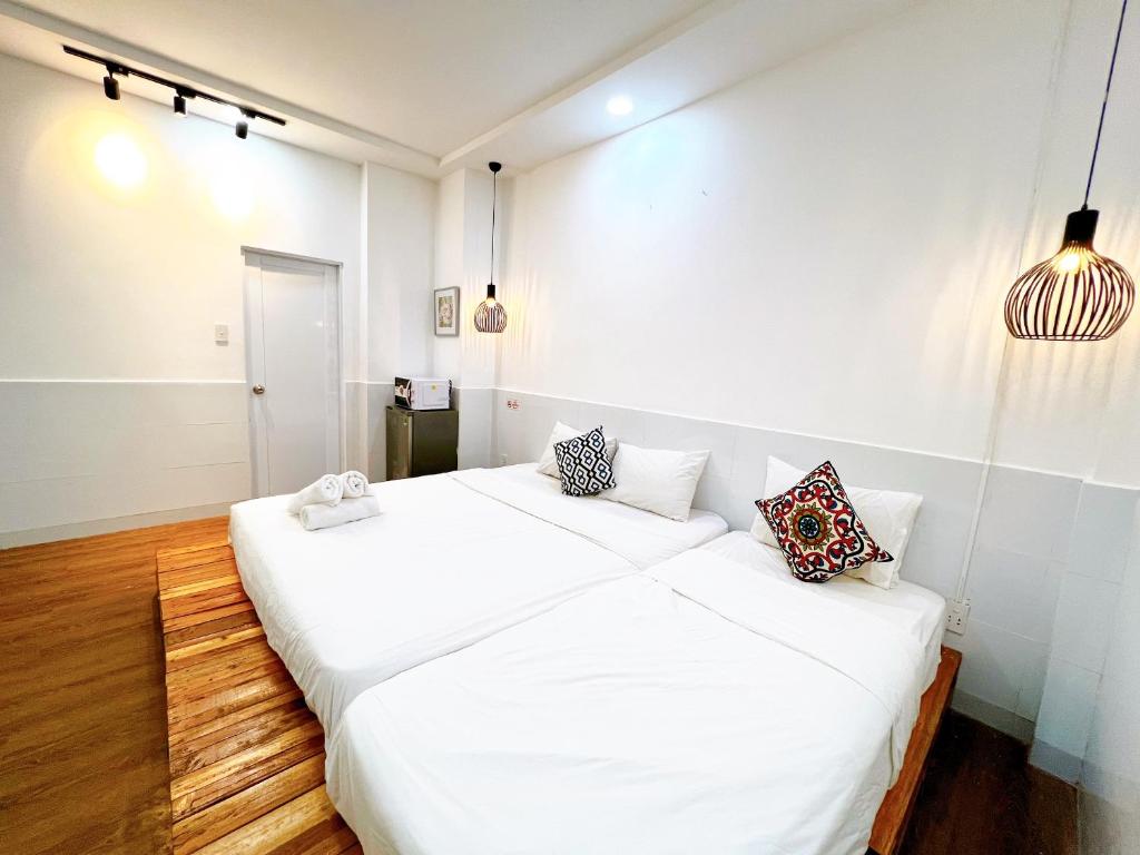 two beds in a room with white walls and wooden floors at Maison Bùi Viện in Ho Chi Minh City