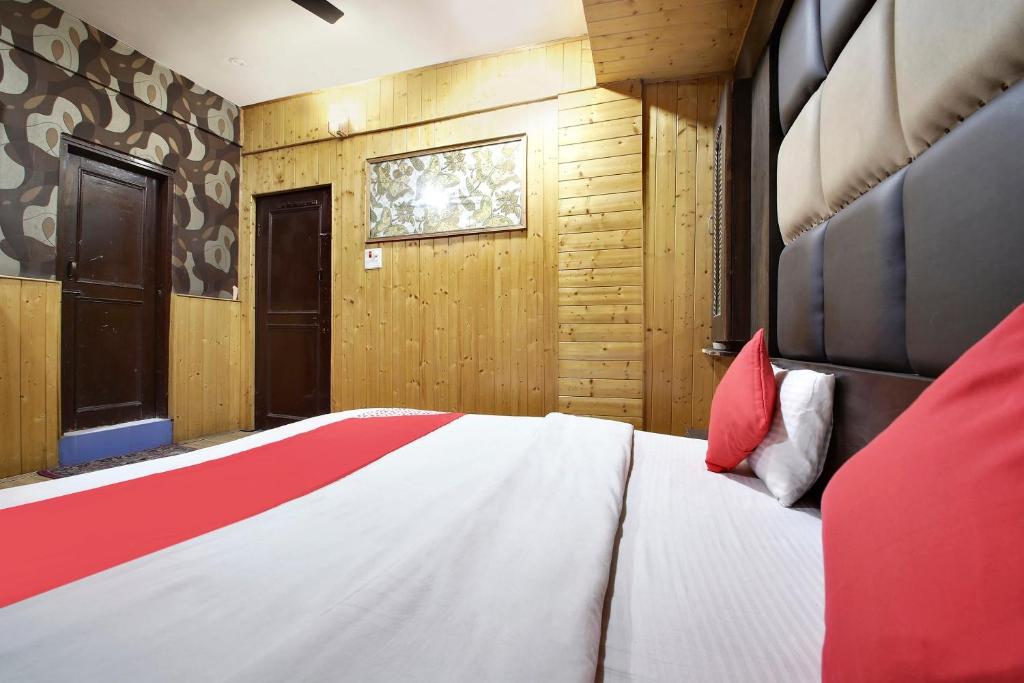 OYO Hotel Azad في جامو: غرفة نوم بسرير كبير ومخدات حمراء