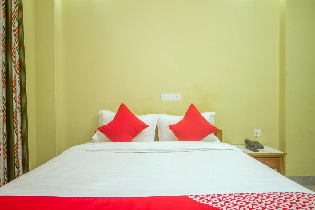una camera da letto con un letto con cuscini rossi di Capital O Parasol Inn a Tādong