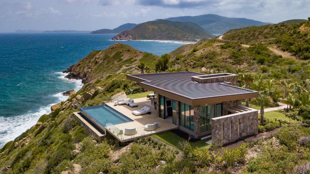 a house on a cliff next to the ocean at Oil Nut Bay in Virgin Gorda