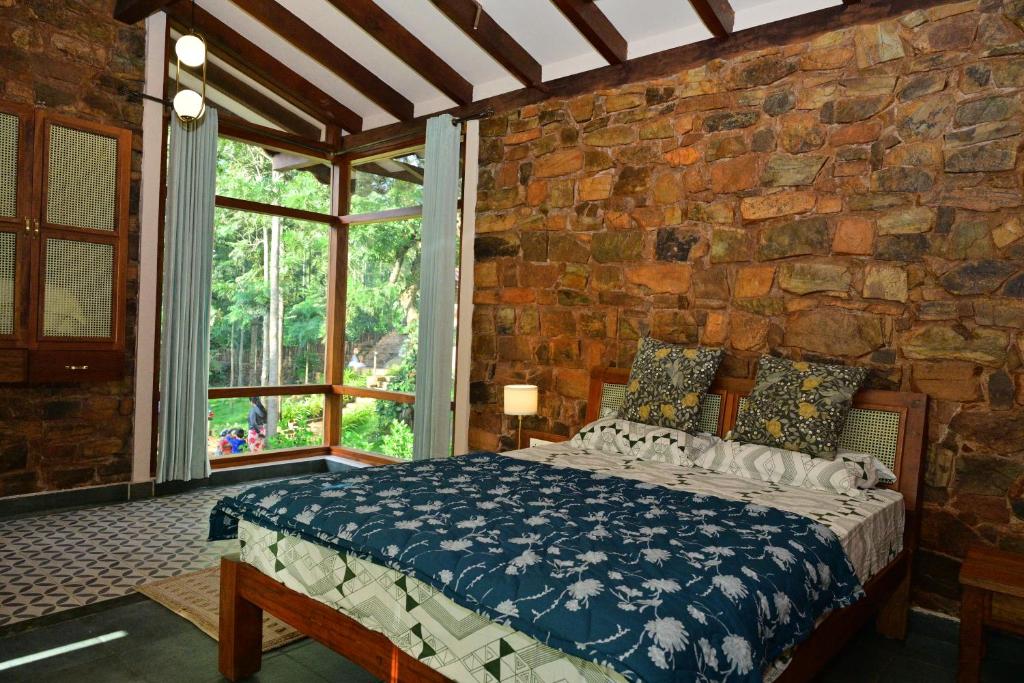 een slaapkamer met een bed in een stenen muur bij Sereno Pool Villa Chikmagalur in Chikmagalūr