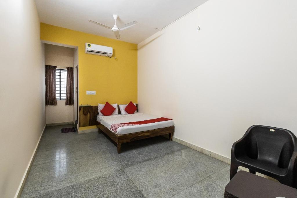 a bedroom with a bed and a yellow wall at OYO Supriya Lodge in Hassan