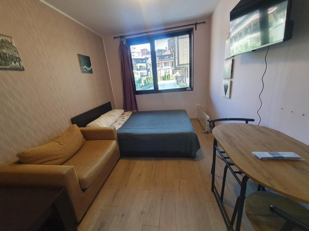 a room with a bed and a couch and a table at Mechka ski apartment in Bansko