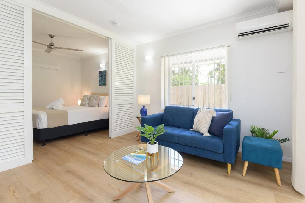 a living room with a couch and a table and a bed at 1 Bedroom ground floor apartment @ Palm Villas in Port Douglas