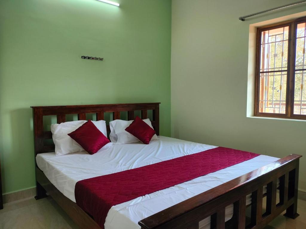 AthmA ArunA - Homestay Tiruvannamalai في تيروفانمالي: غرفة نوم بسرير ومخدات حمراء وبيضاء