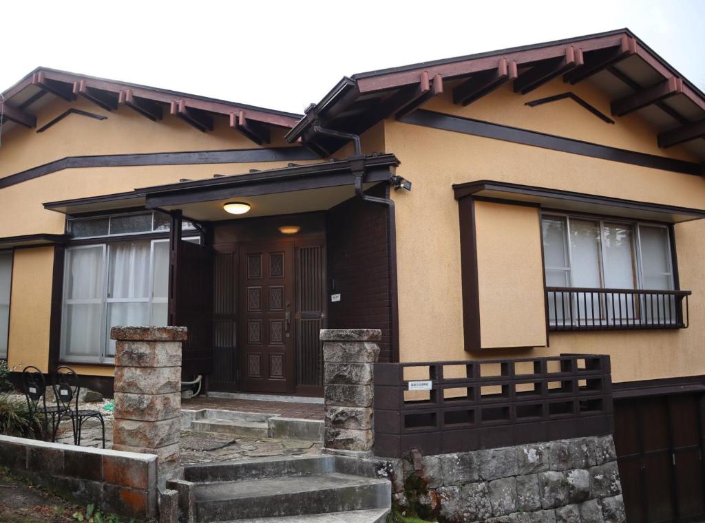 une maison avec une porte marron et une clôture dans l'établissement NEW OPEN『天然温泉』芦ノ湖畔の完全貸切別荘, à Hakone
