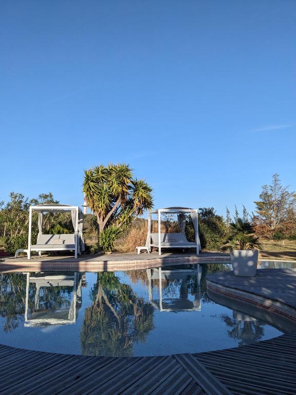 - une piscine avec 2 chaises blanches et une table dans l'établissement Gite L olivier, à Baho