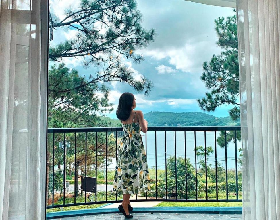 Una mujer con un vestido parada en un balcón en Romeo & Juliet Dalat Resort en Da Lat