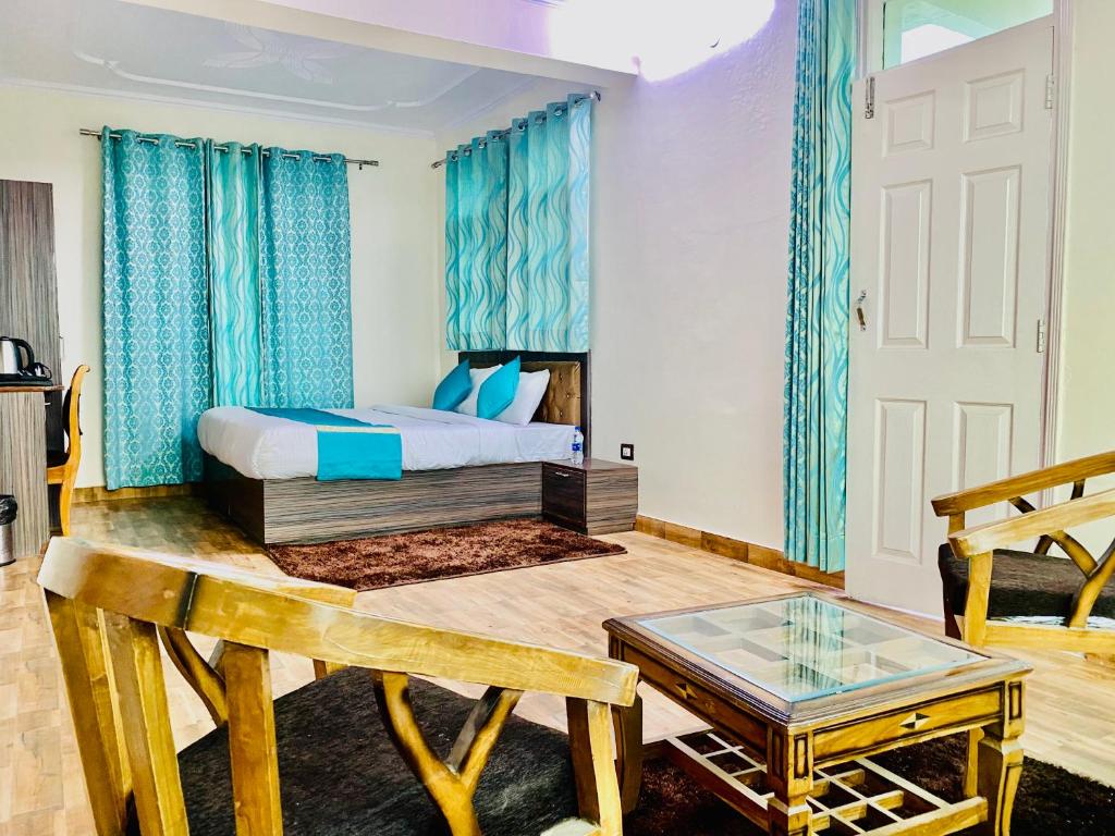 a bedroom with a bed with blue curtains and a table at Royal Green Valley View Mashobra in Shimla