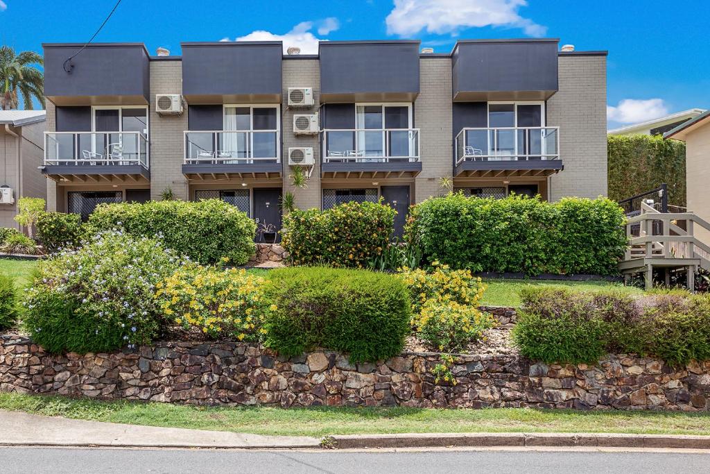 an apartment building with a stone wall and bushes at Unit 1 Sunbird on Lamond in Airlie Beach