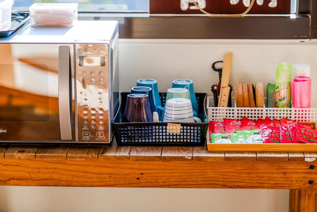 a counter with a microwave and a tray of utensils at Southern Sun Homestay North in Kenting