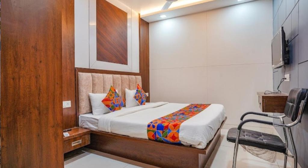 um quarto com uma cama e uma televisão em Hotel Coral em Indore