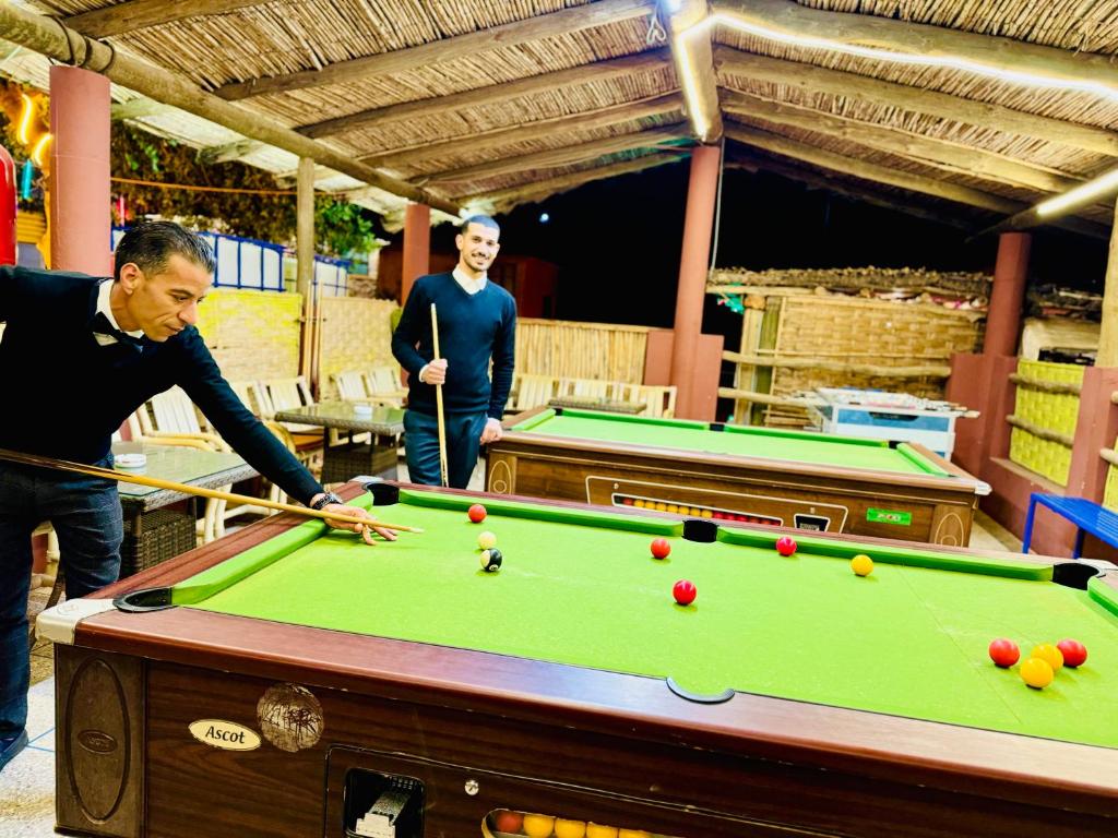 a man playing a game of pool with a cue at maison d'hôtes yamine in Beni Mellal
