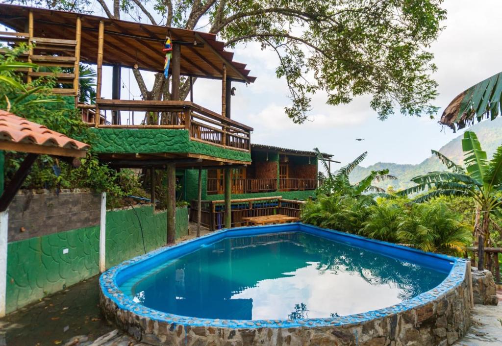uma casa com piscina em frente a um edifício em Hostal El Santuario em Minca
