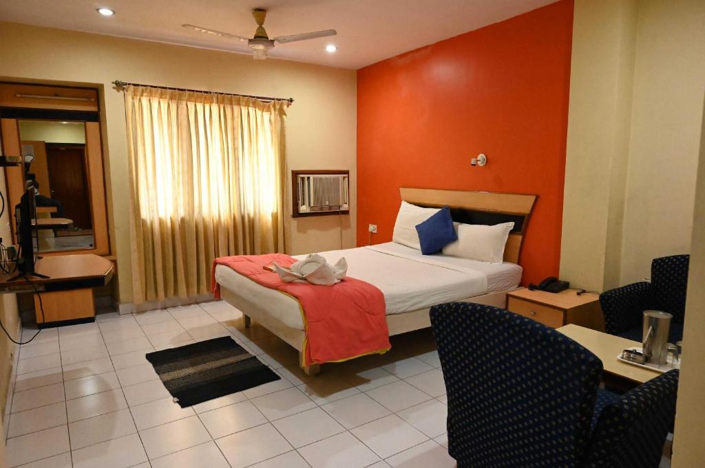 um quarto com uma cama com uma parede vermelha em OYO Hotel Nico em Port Blair