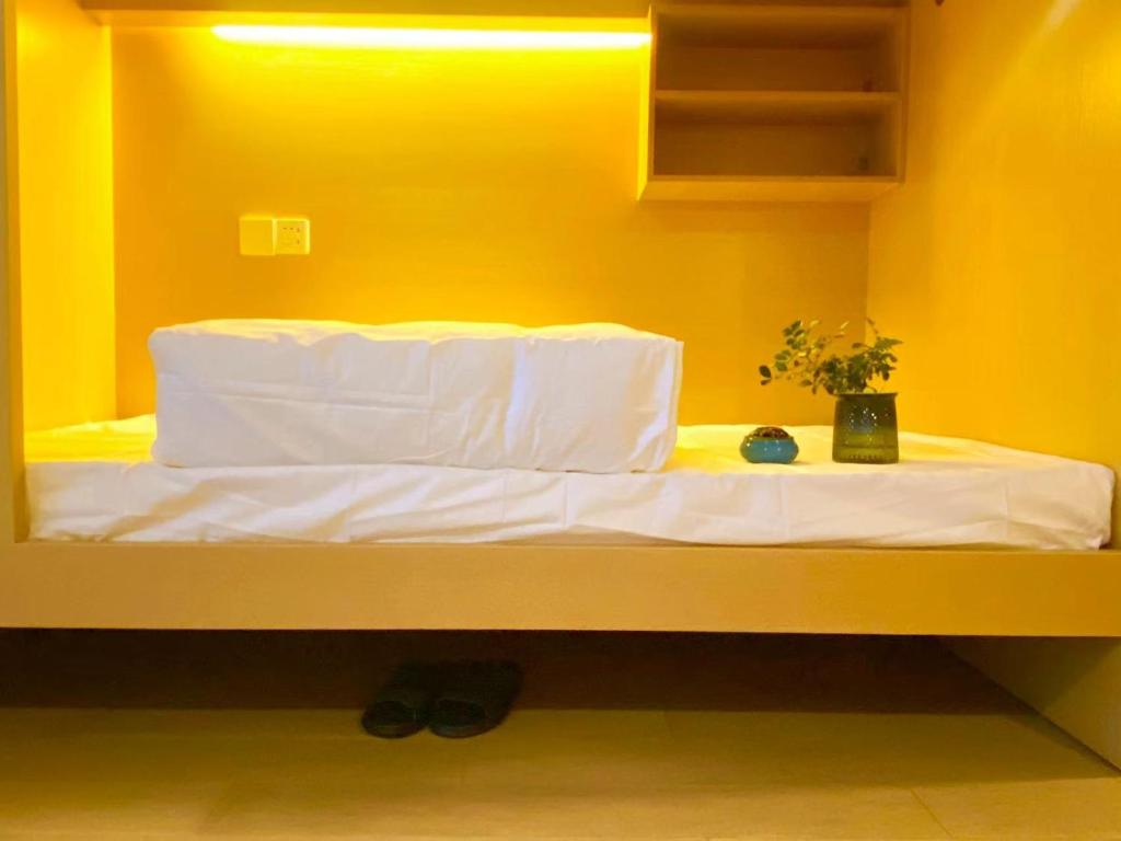 Ce lit se trouve dans une chambre dotée d'un mur jaune. dans l'établissement Hangzhou inn Time Youth Hostel, à Hangzhou