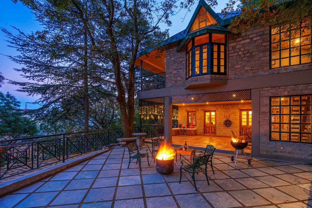 a house with a fire pit on a patio at StayVista at Paris Villa with Pvt Pool & Valley View in Kasauli