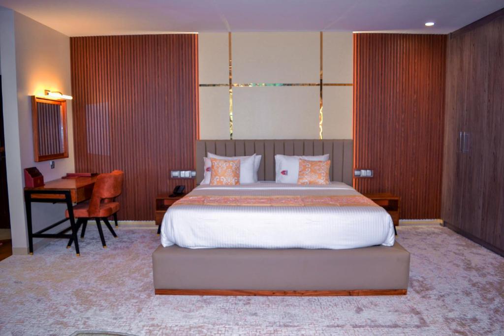 a bedroom with a large bed and a desk at KingJada Hotels And Apartments Ltd in Dar es Salaam