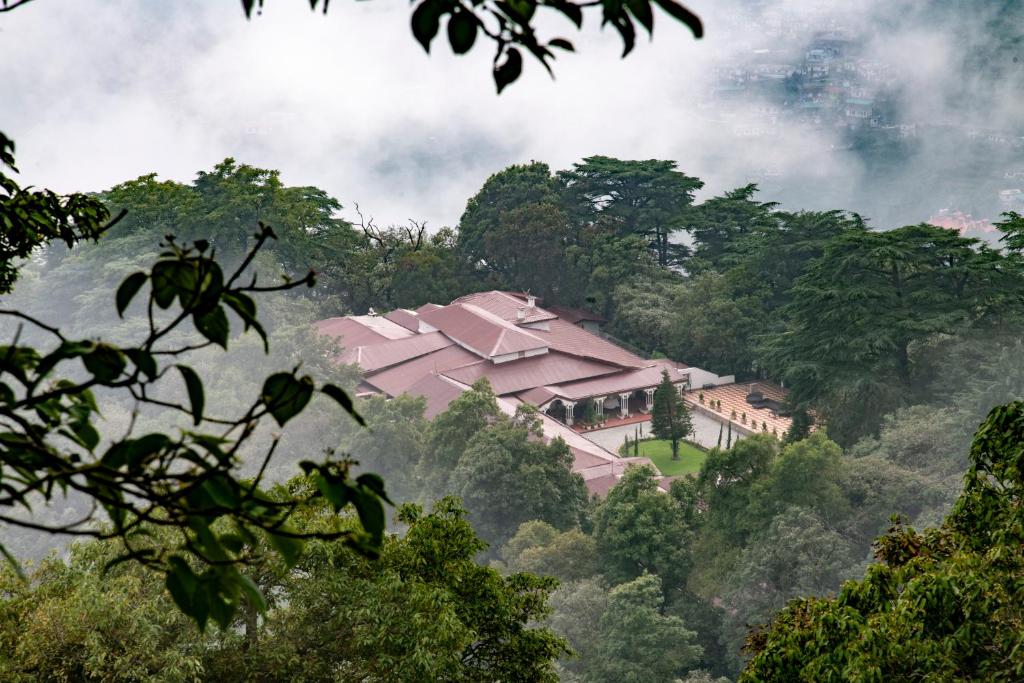 a large building in the middle of a forest at The Claridges Nabha Residence in Mussoorie