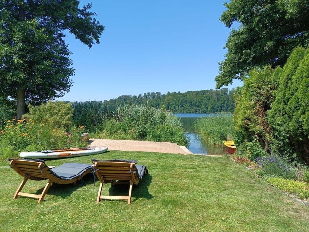 two chairs and a table on the grass next to a lake at Welcoming holiday home by the sea in Godern