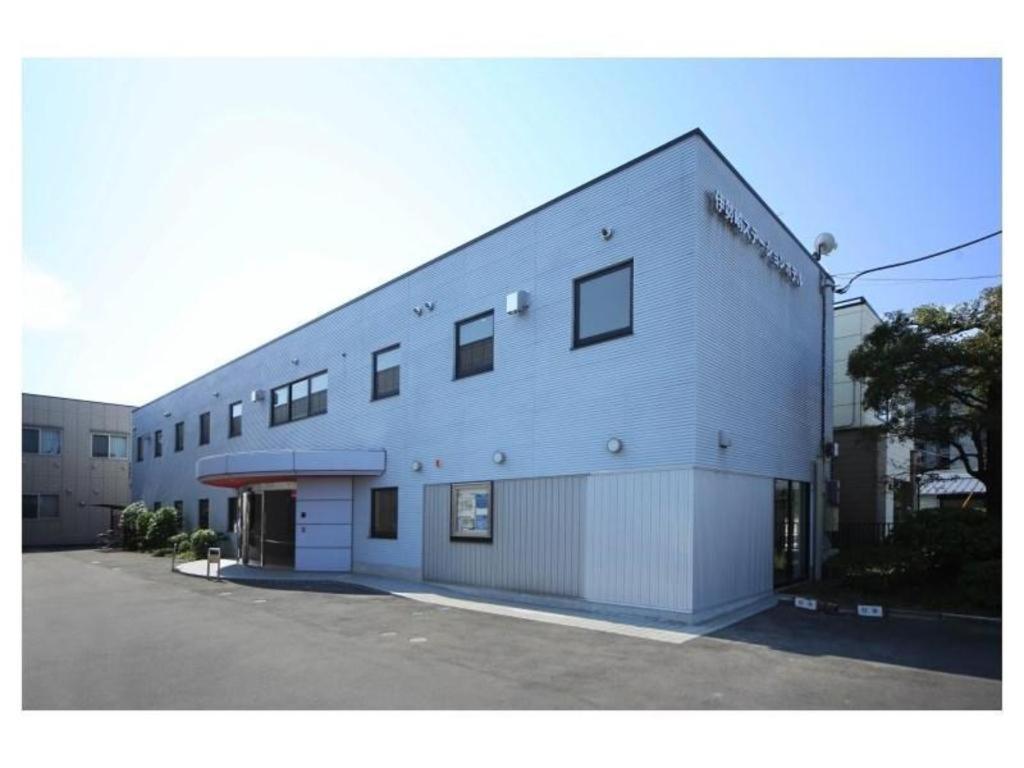a large white building with a parking lot at Isesaki Station Hotel in Isesaki