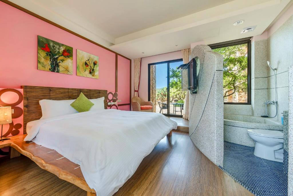 a bedroom with a bed and a bathroom with a tub at Southern Sun Homestay North in Kenting