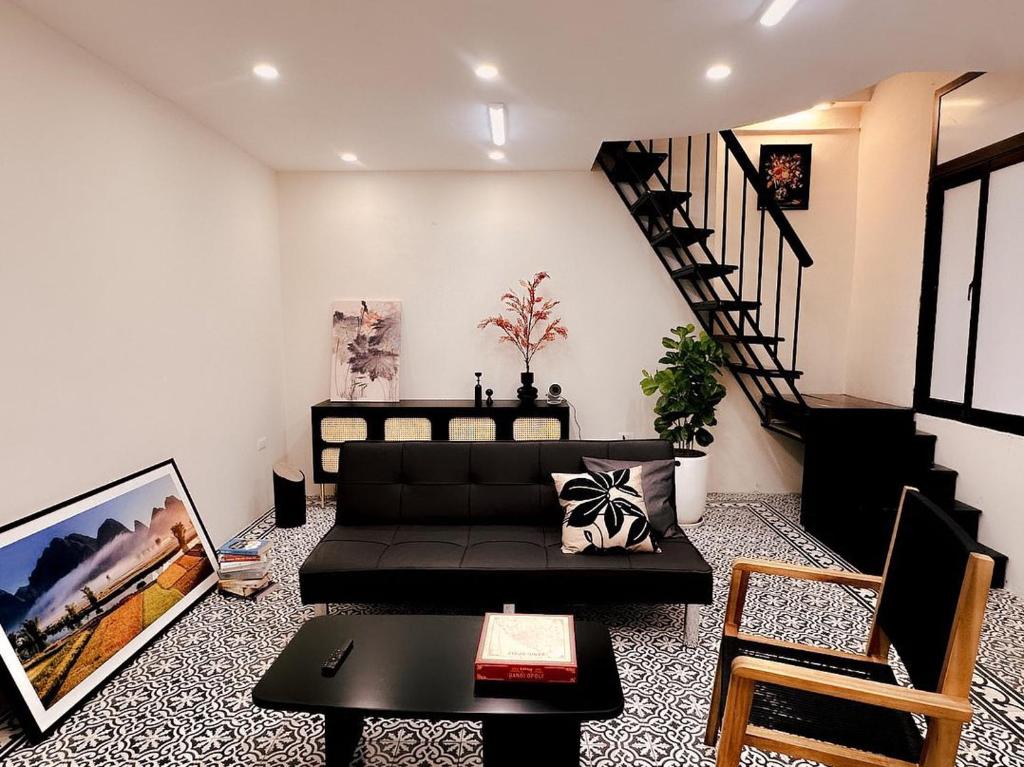 a living room with a black couch and a staircase at Old Quarter Centre Duplex 2BR w Netflix_Wifi in Hanoi