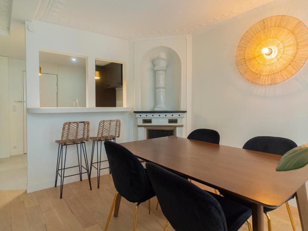 cocina y comedor con mesa de madera y sillas en Appartement d'architecte au cœur de Paris 9, en París