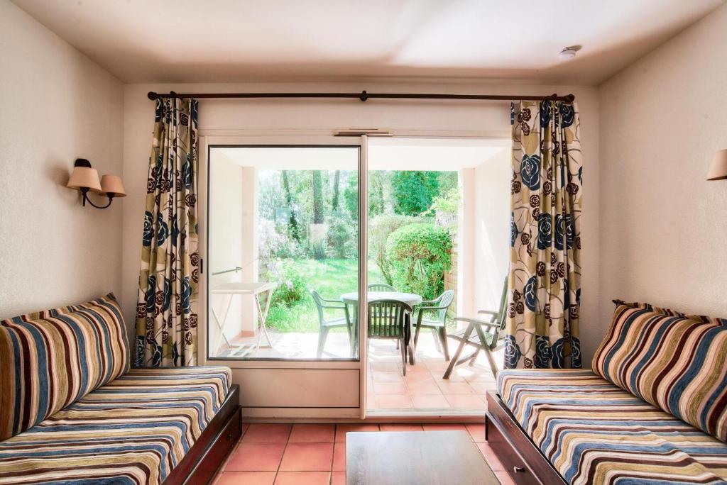 - un salon avec deux canapés et une porte coulissante en verre dans l'établissement Le Domaine du Golf de Pinsolle - maeva Home - Appartement 2 pièces 5 personnes - Confort MAE-7414, à Soustons