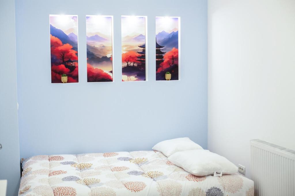 a bedroom with a bed with three paintings on the wall at Cozy Studio Apartment in Arad City Center in Arad