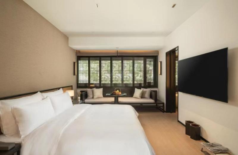 a bedroom with a large white bed and a couch at Yihe Riverside Suzhou in Suzhou