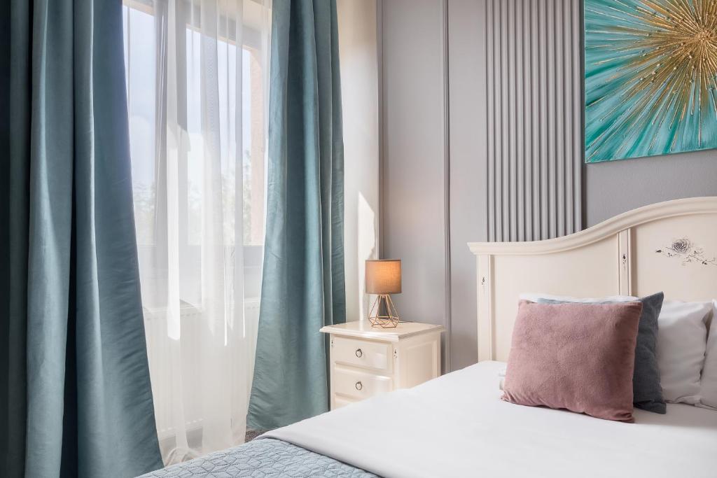 um quarto com uma cama e uma janela com cortinas azuis em Moonlight Central Apartments em Oradea