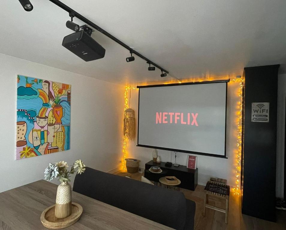 ein Wohnzimmer mit einem Bildschirm mit einem Netflix-Schild in der Unterkunft Appartement Proche Disney Paris Vidéo-Projecteur in Bussy-Saint-Georges