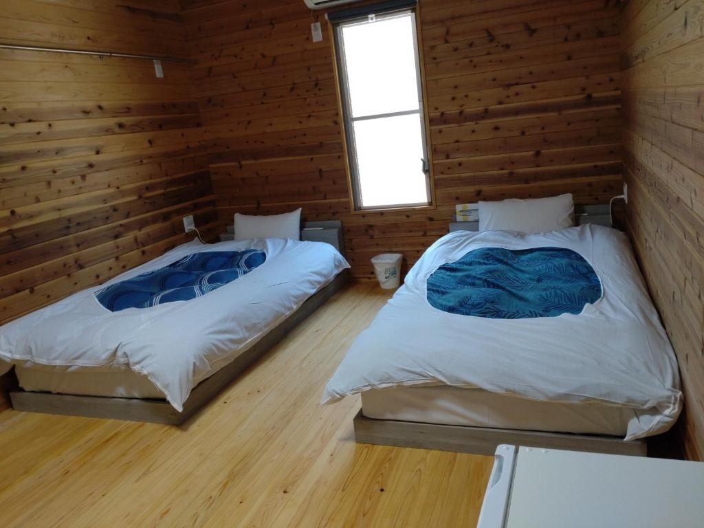 Duas camas num quarto com paredes de madeira em Naoshima Accommodation Menjuku Ura - Vacation STAY 92589v em Naoshima