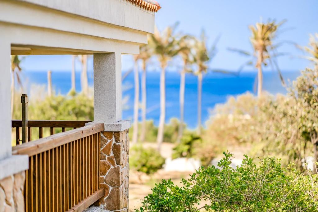 a porch of a house with palm trees and the ocean at Southern Sun Homestay North in Kenting