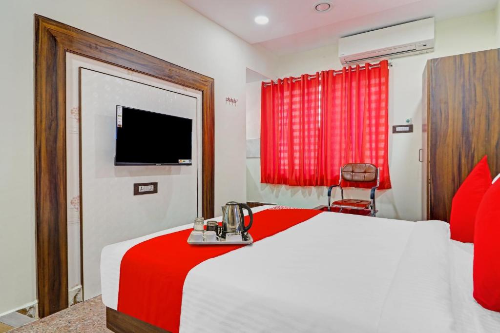 a bedroom with a red and white bed and a television at Heavens Inn Near Rasoolpura metro station in Hyderabad