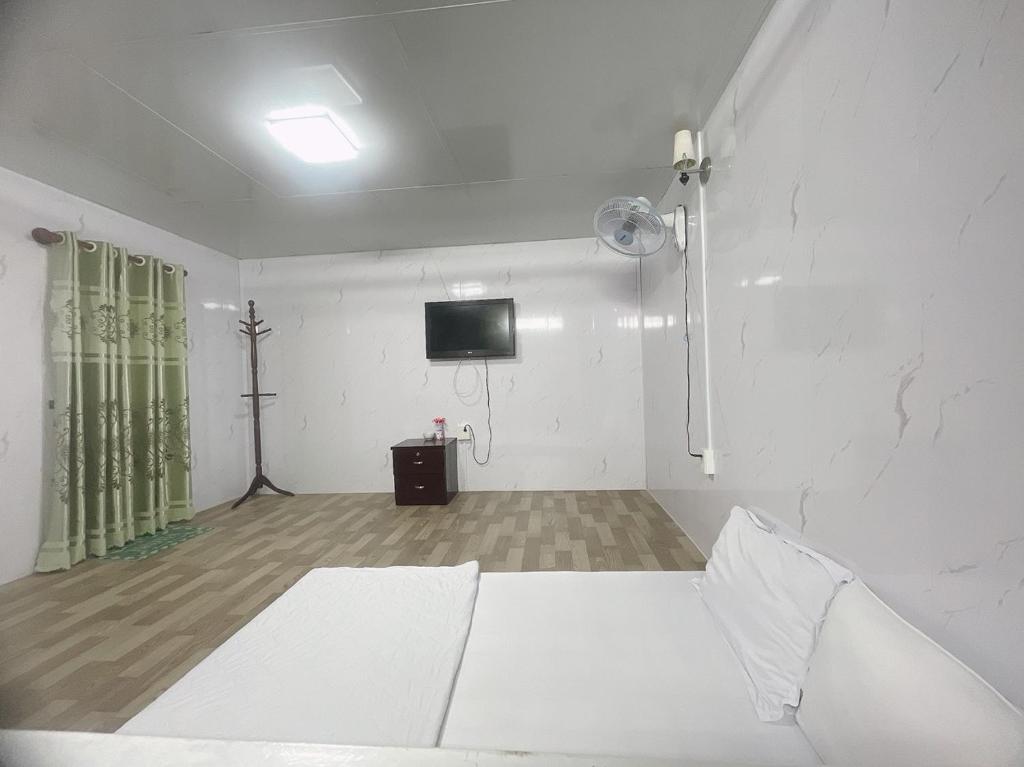 a white room with a bed and a tv at TRUNG LUONG HOMESTAY in Trung An