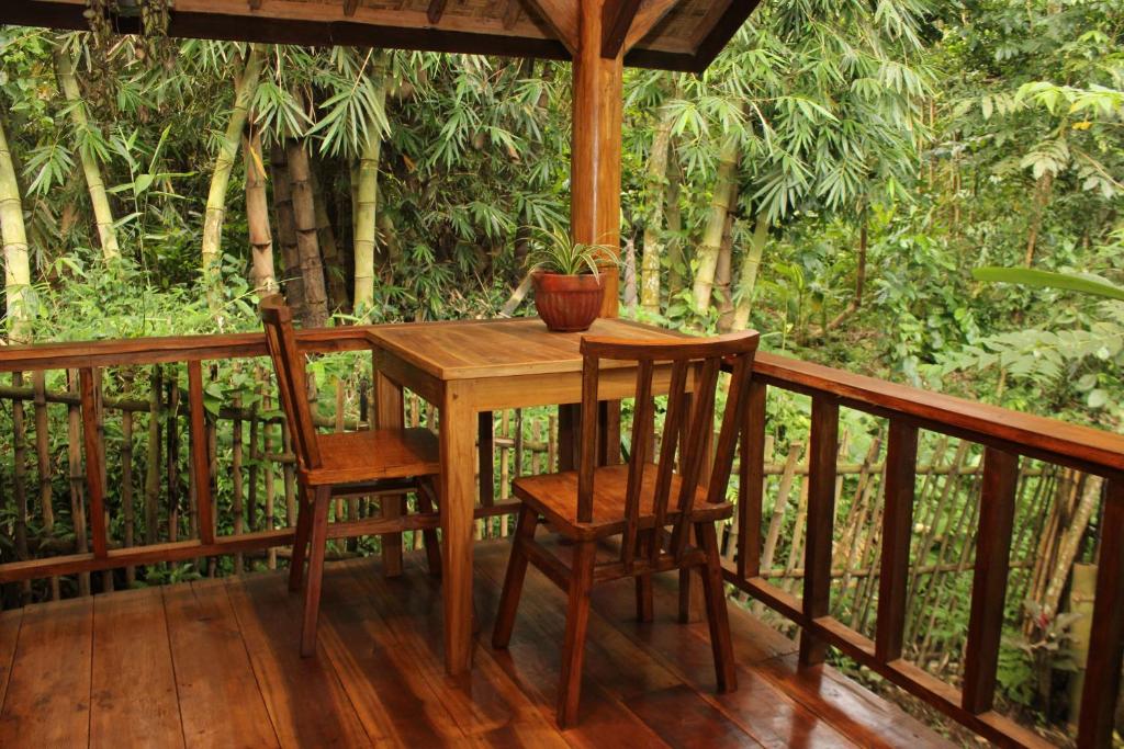 een houten tafel en 2 stoelen op een veranda bij Santai House in Tetebatu