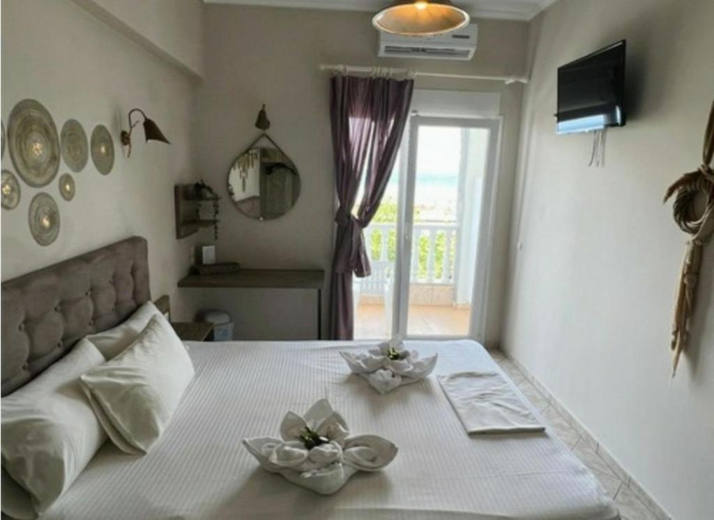 a bedroom with a bed with two flowers on it at Dionisos Hotel in Nei Poroi