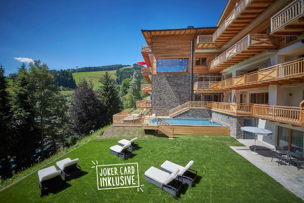 uma casa com um relvado com cadeiras e uma piscina em AlpenParks Hotel & Apartment Sonnleiten em Saalbach-Hinterglemm