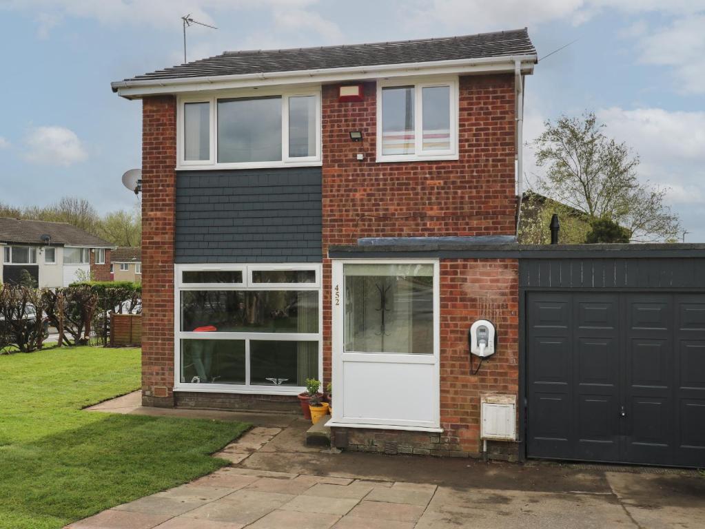 a brick house with a white door and a garage at Cosmic Pearl in Garforth